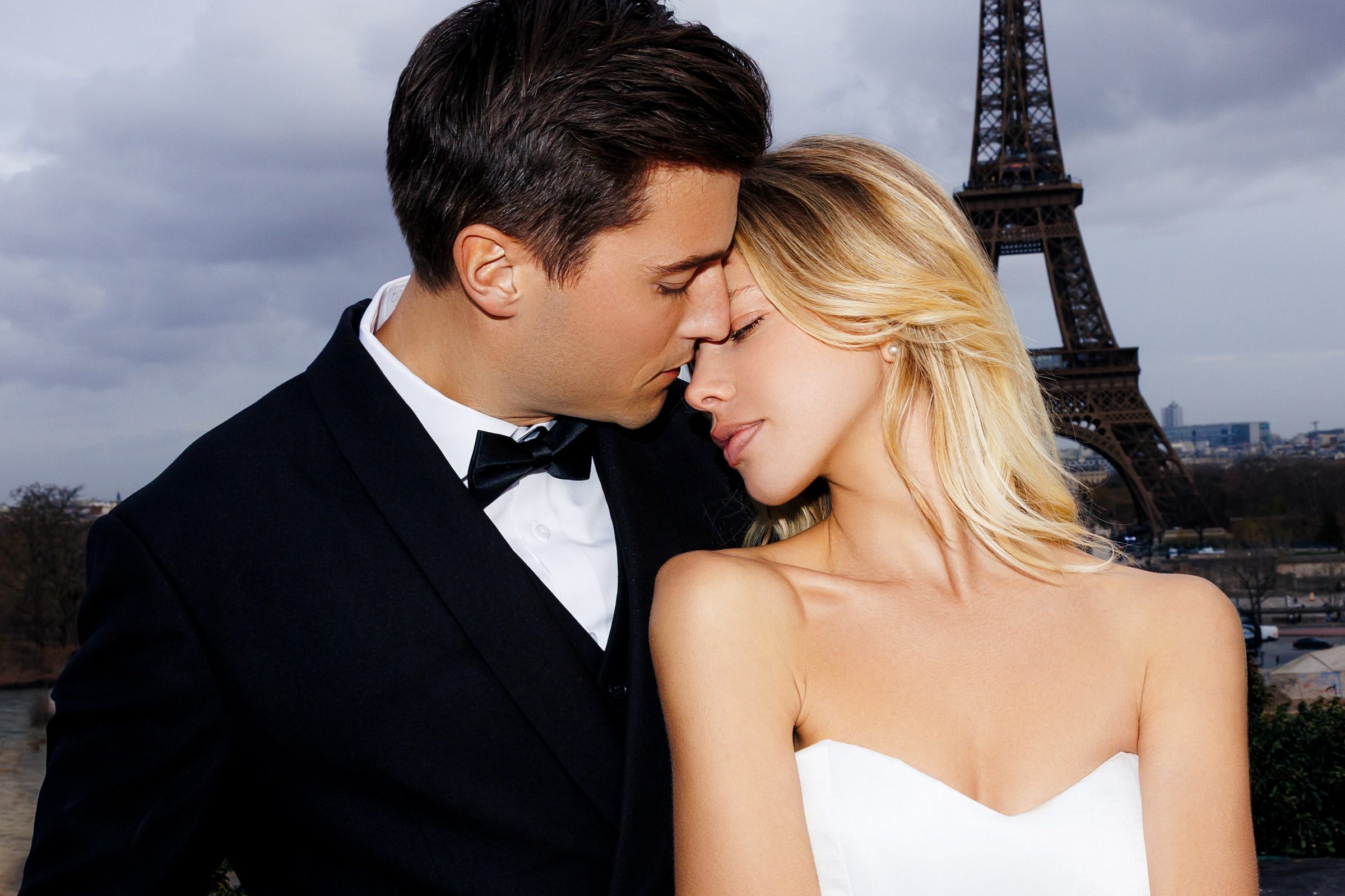 Bride and groom embracing at dusk with the Eiffel Tower behind them
