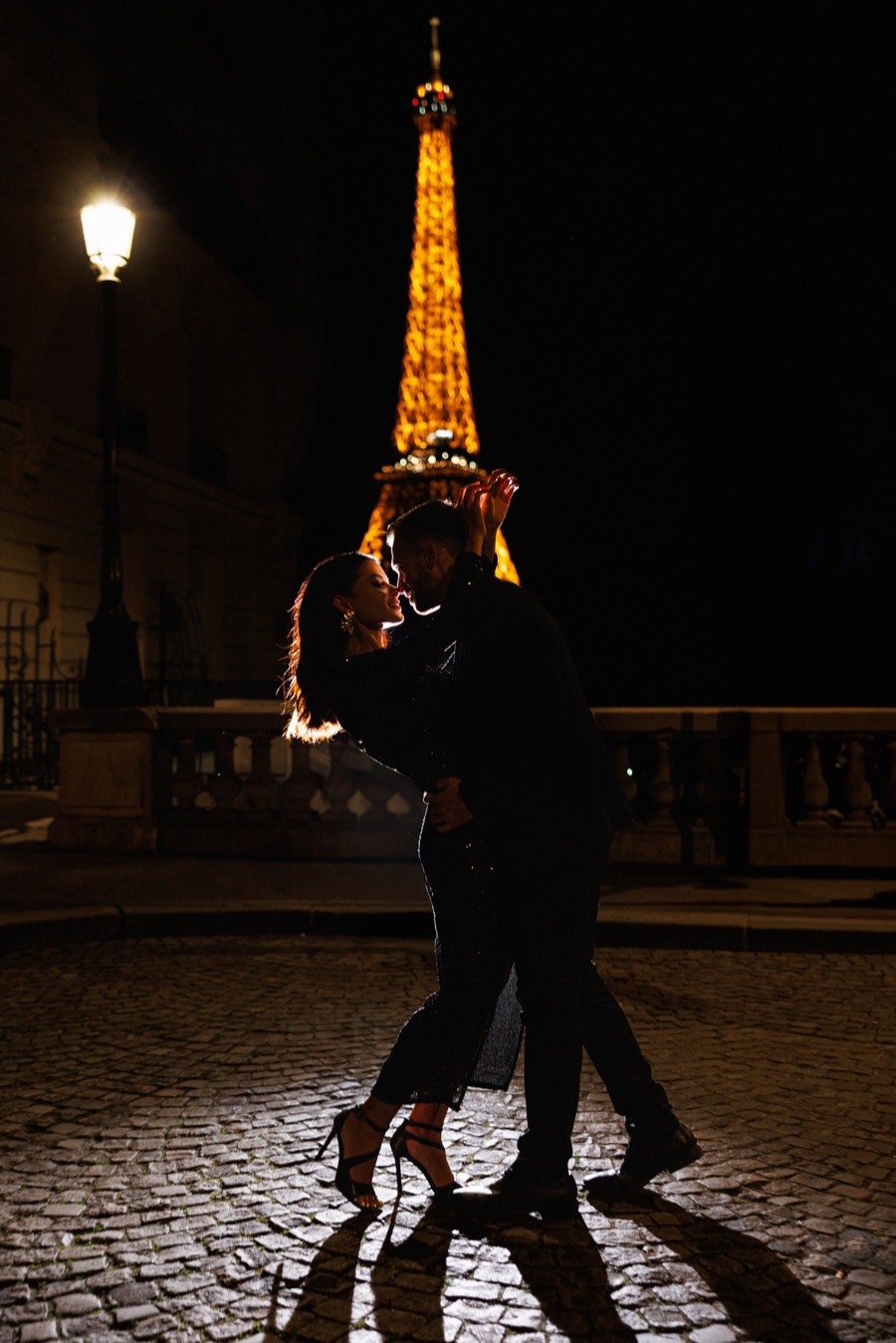 Couple dancing in front of the illuminated Eiffel Tower at night