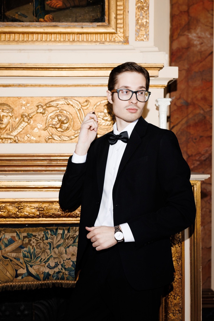 Groom in black tie by a gilded Parisian fireplace