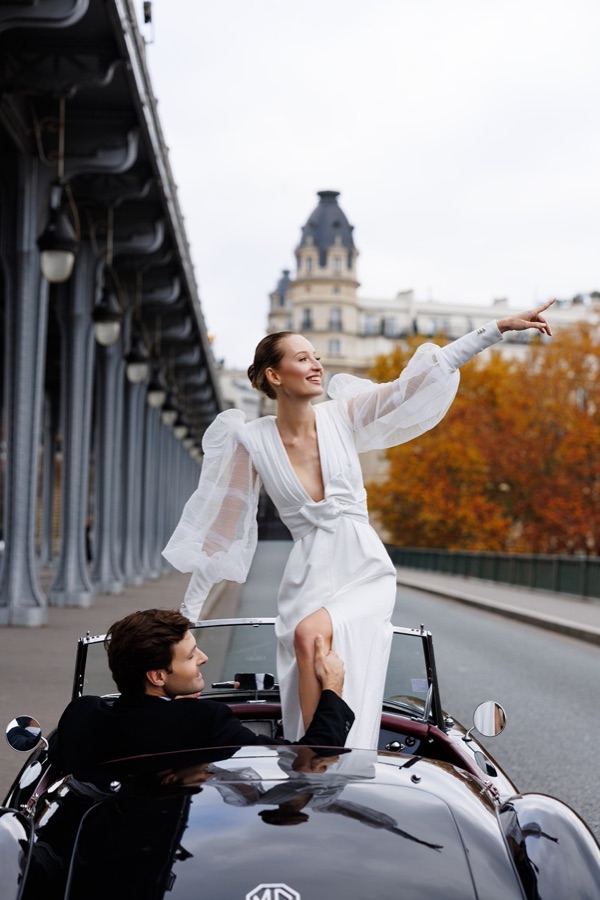 Bride standing in a vintage convertible on a Paris bridge